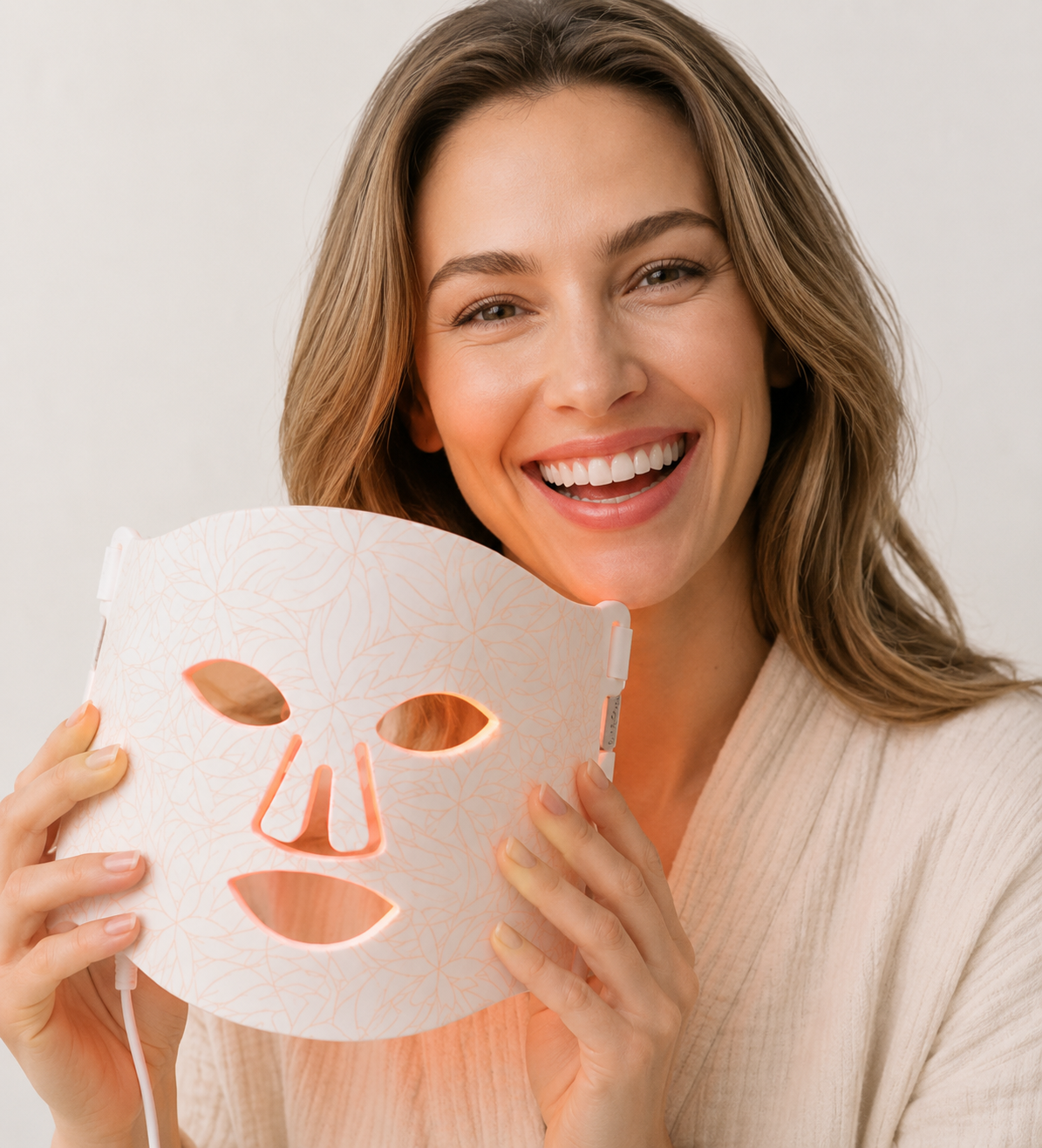 Woman smiling with LED face mask for a light therapy skincare routine